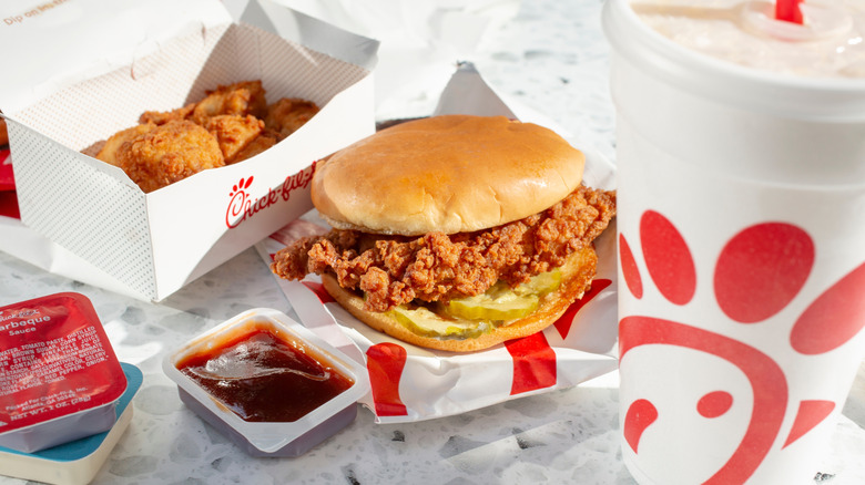 Chick-fil-A sandwich with nuggets. Barbeque sauce, and drink.