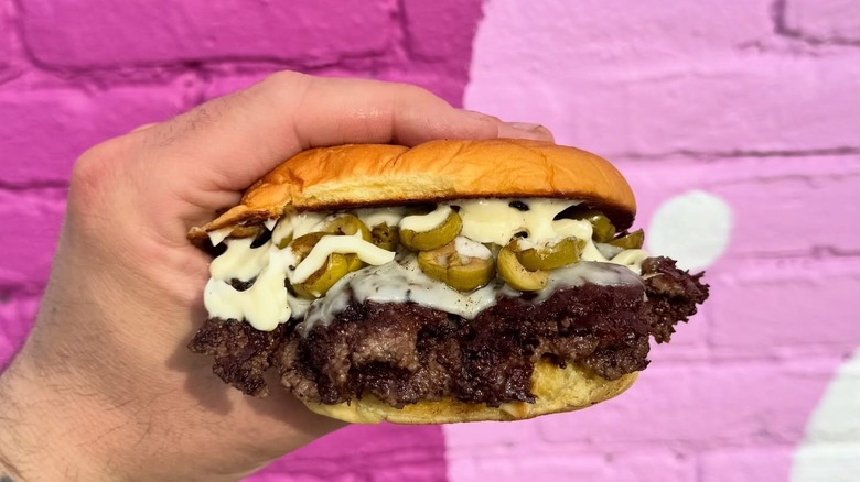 A hand holding an Olive Burger.