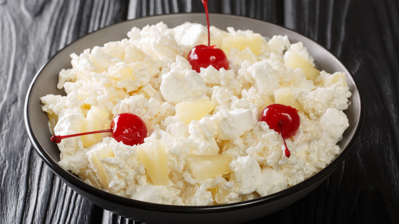 A bowl of glorified rice with pineapple and maraschino cherries