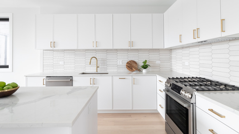 A completely white kitchen with white countertops, cupboards, and an all white island
