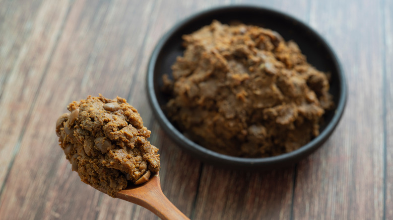 A spoon of doenjang next to a bowl
