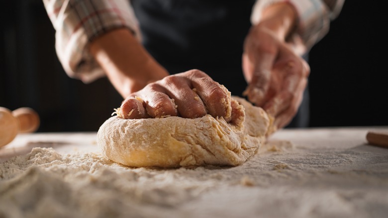 a close up of a hand rolling out pizza dough