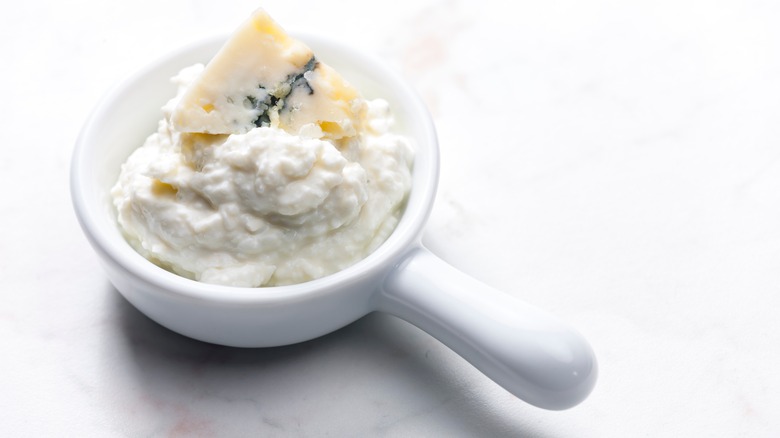Wedsge of blue cheese on top of white dip