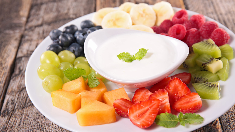 Creamy fruit dip on platter with cut various fruits