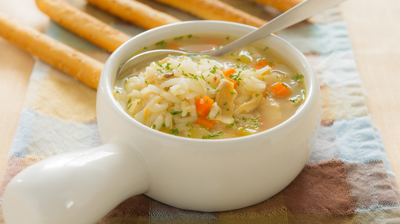 White bowl of chicken and rice soup with spoon