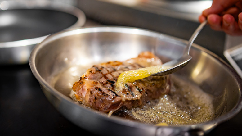 Spooning butter over steak for basting