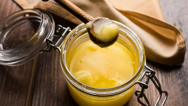 Clear pot of clarified butter on wooden table