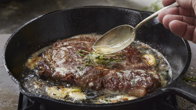 Spooning butter over steak