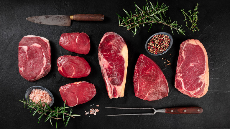 Different cuts of steak on black table