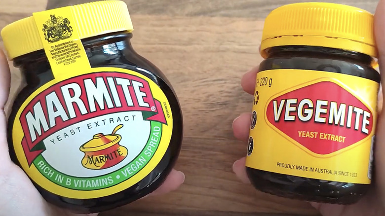 Two hands holding jars of Marmite and Vegemite jars