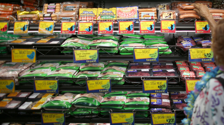 A customer reaches for sausages in the Trader Joe's meat aisle