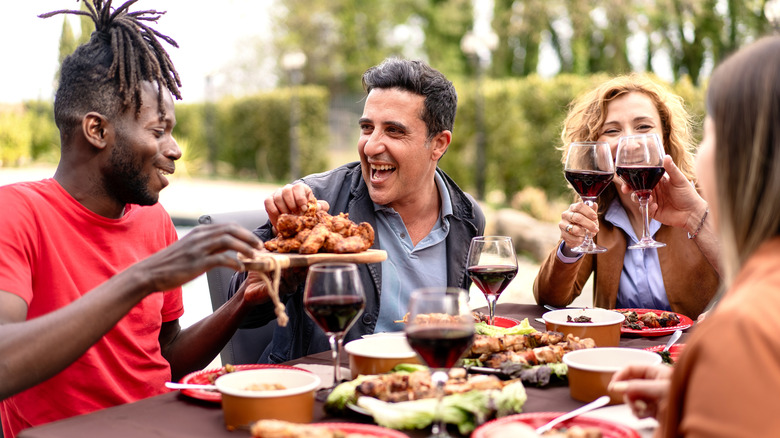 friends enjoying red wine and dinner outside