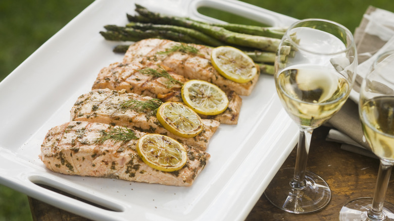 grilled salmon and asparagus with two glasses of white wine