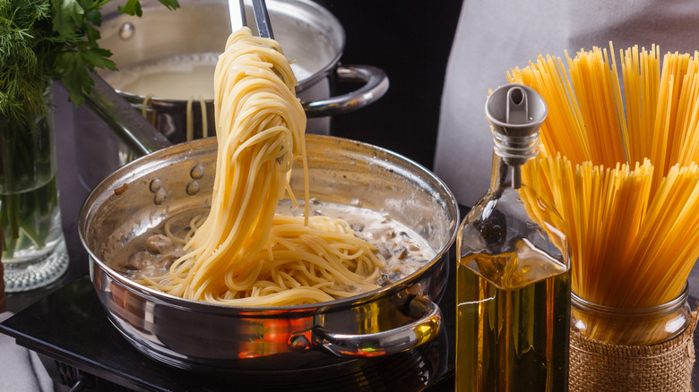 Tongs grabbing noodles from pot