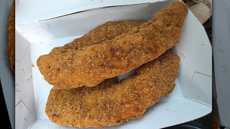 Three McDonald's McCrispy strips sit in a paper to-go box