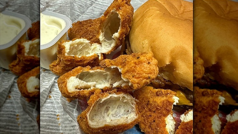 A pile of hollow Wendy's chicken nuggets next to a burger