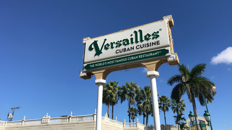 Versailles Restaurant sign against a blue sky and palm trees