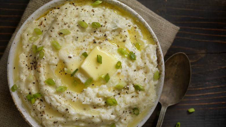 Bowl of mashed potatoes topped with melted butter