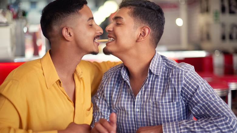 two men sharing French fry