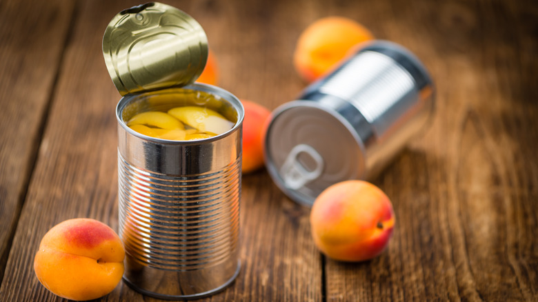canned and fresh peaches on wooden table