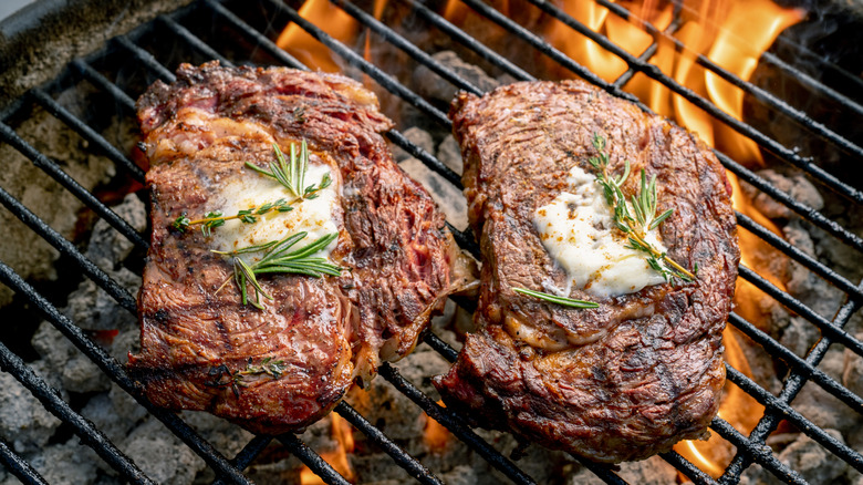 Two ribeye steaks with butter on a grill