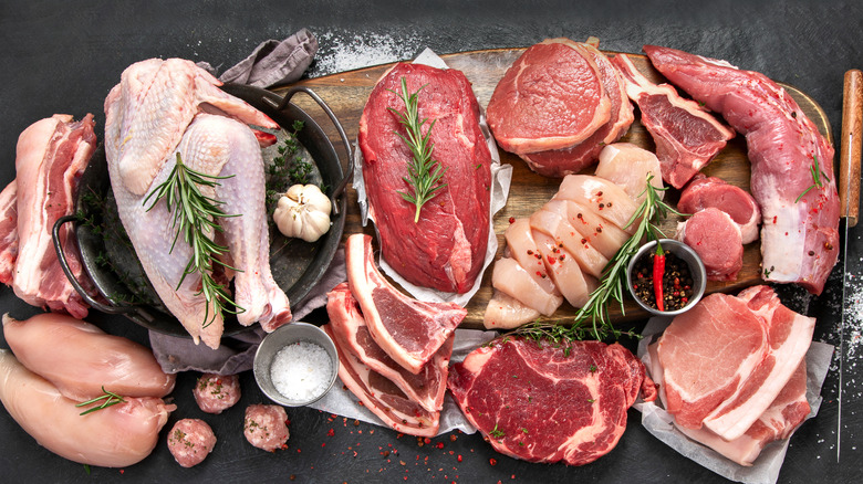 an array of different kinds of meat, including poultry, steak, pork, and more, topped with fresh herbs and spices