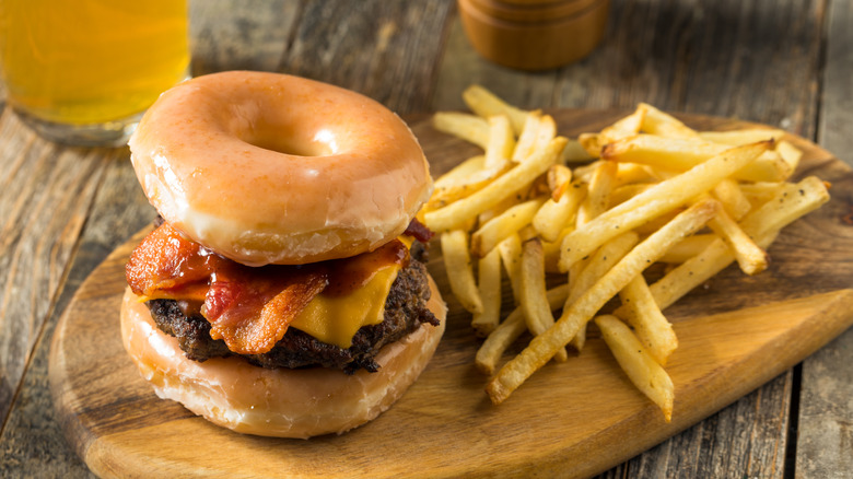A cheeseburger served on a donut bun with a side of french fries