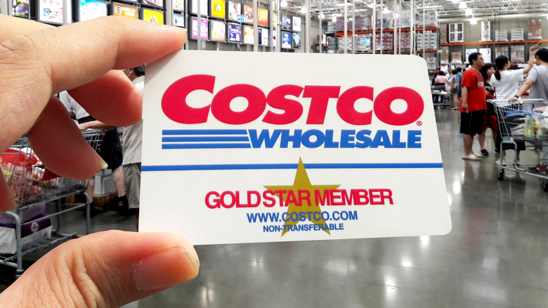 Hand holding a Costco membership card in the warehouse