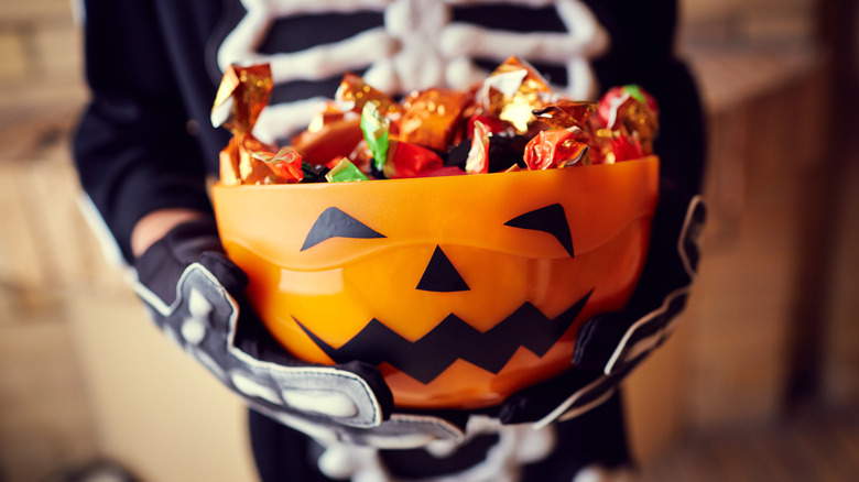 child holding halloween candy bowl