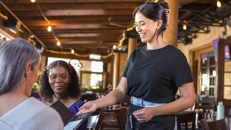 Restaurant server taking bill from diners