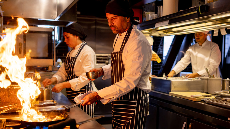 Restaurant line cooks with flaming pan
