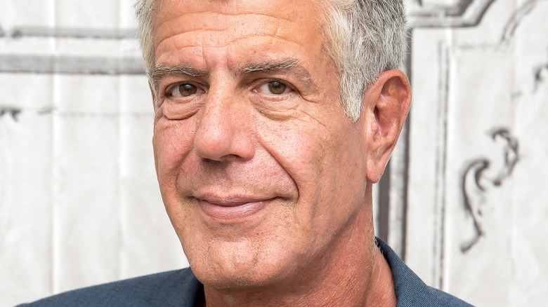 Anthony Bourdain smiling in front of building