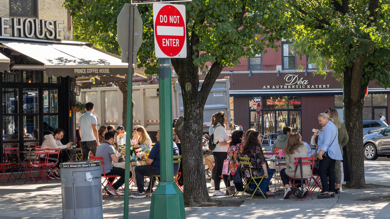 Arthur Avenue in the Bronx has people sitting outside enjoying food at an eatery.