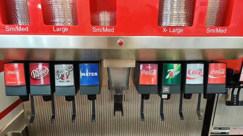 A soda machine with a line of Coca-Cola products and 7-Up.