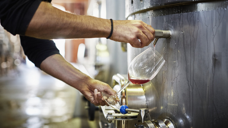 wineglass being filled from fermentation tank