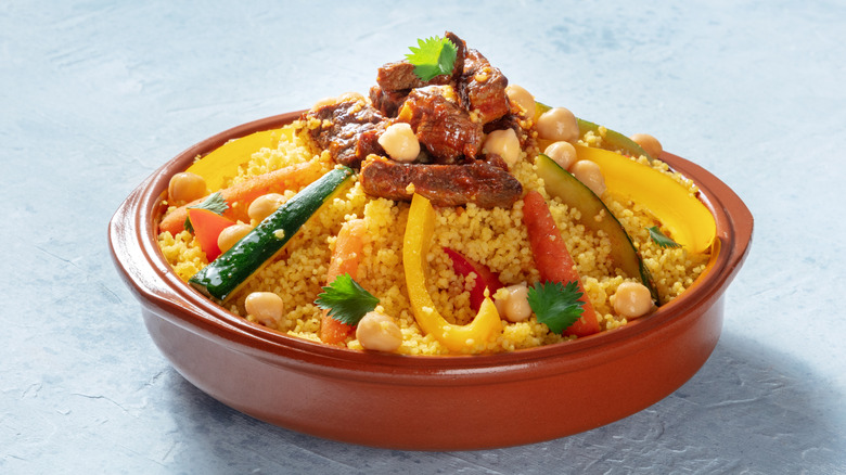 Clay pot of Algerian couscous with veggies, roasted meat, and chickpeas
