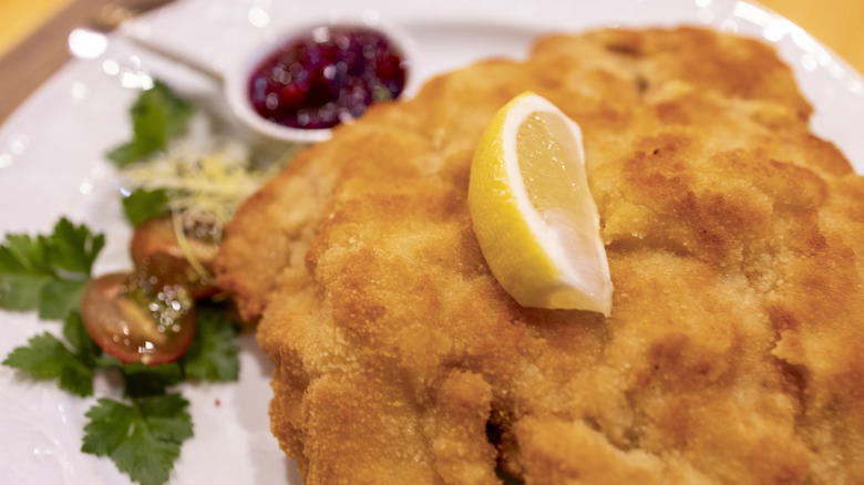 Plate of wiener schnitzel with lemon wedges and cranberry sauce