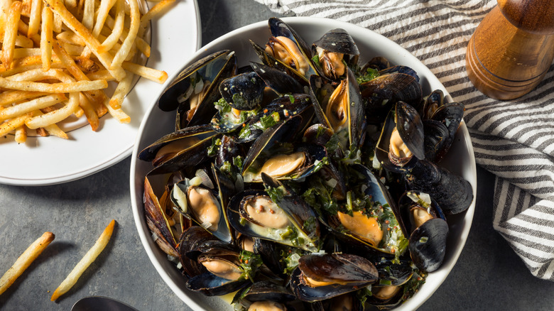 Dish of moules-frites with mussels in white wine sauce and fries