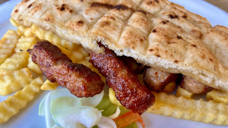 Traditional Ćevapi with fries, bread, and vegetables