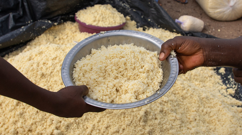 Two hands holding a bowl of attiéké