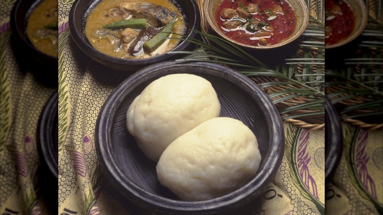 Fufu dumplings in bowl in front of savory soups