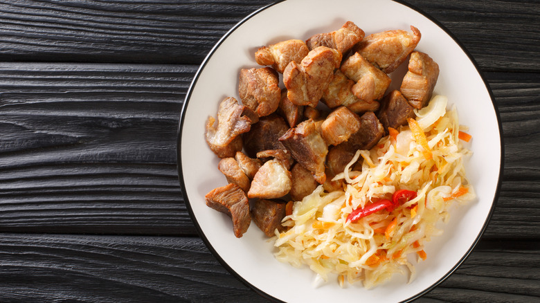Overhead view of a plate of traditional Haitian griot with braised pork shoulder and veggies