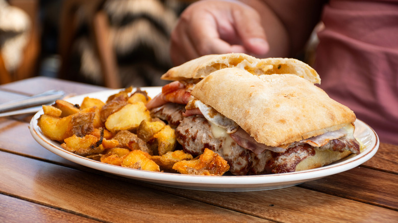 Traditional Chivito sandwich served with potatoes