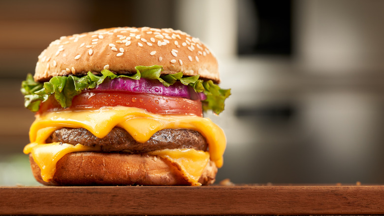 Cheeseburger with lettuce, tomato, and onion on a sesame seed bun