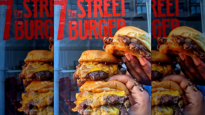 Hands holding two smash burgers from 7th Street Burger