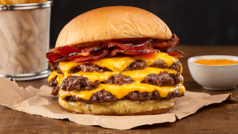 A smash burger with three patties and bacon