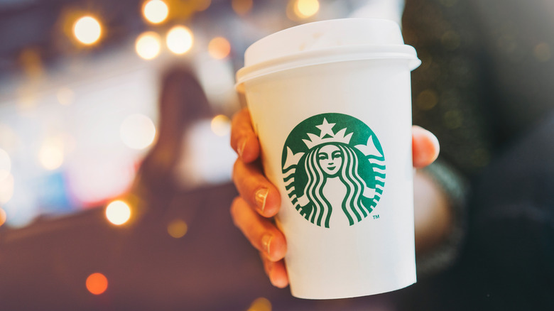 Person holding Starbucks coffee cup 