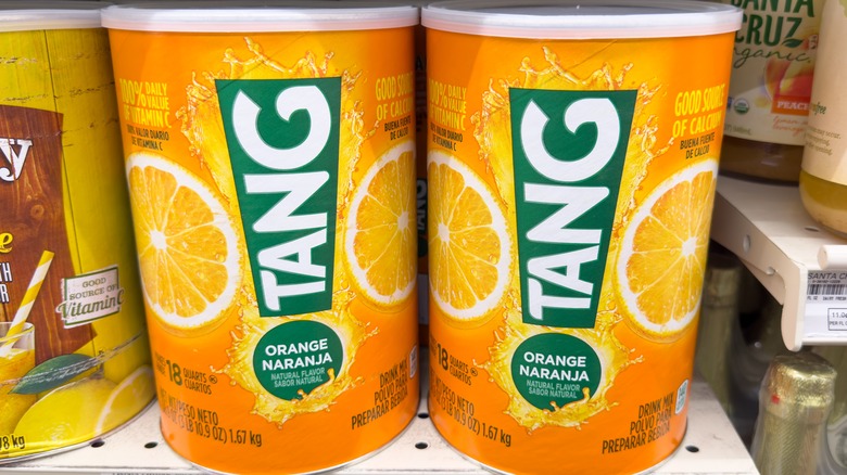 Two cans of Tang orange drink powder on a grocery store shelf