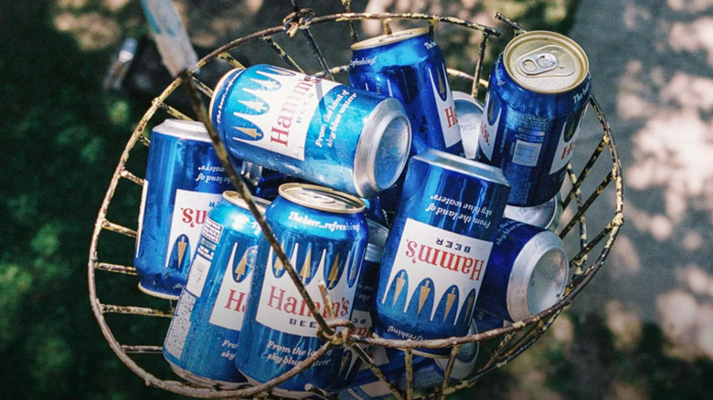 Several cans of Hamm's beer in a wire basket.
