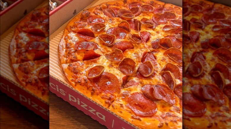 A whole Cicis pepperoni pizza sits in a cardboard to-go box